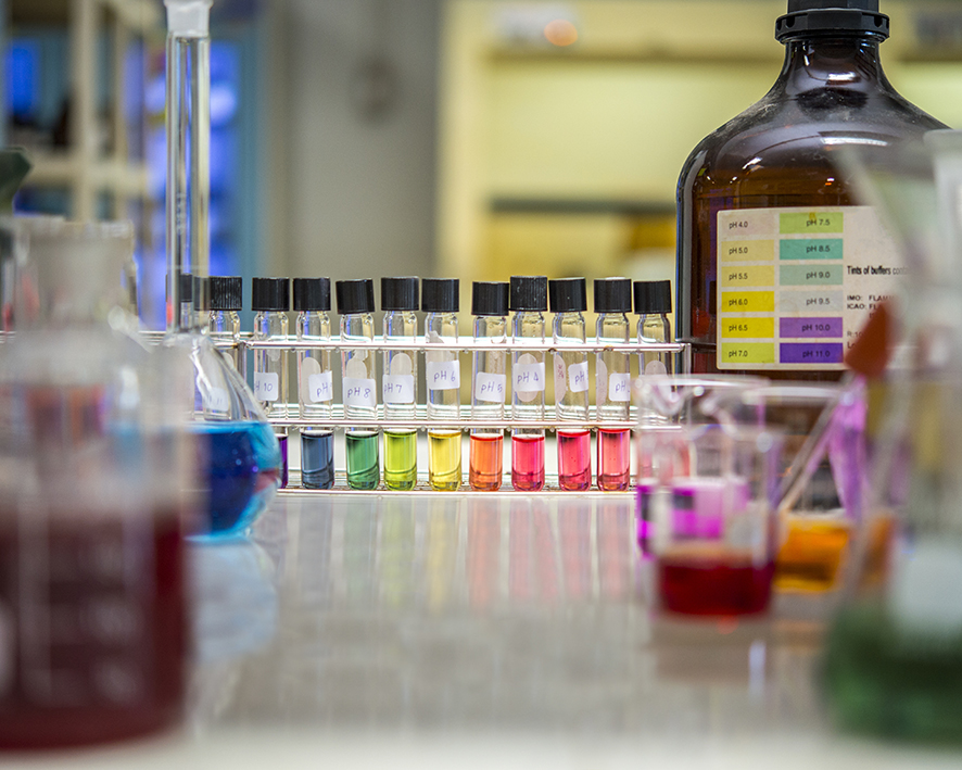 Meranie pH farebných tekutín v skúmavkách a kadičkách a fľašiach v štúdiu s bielym stolom.